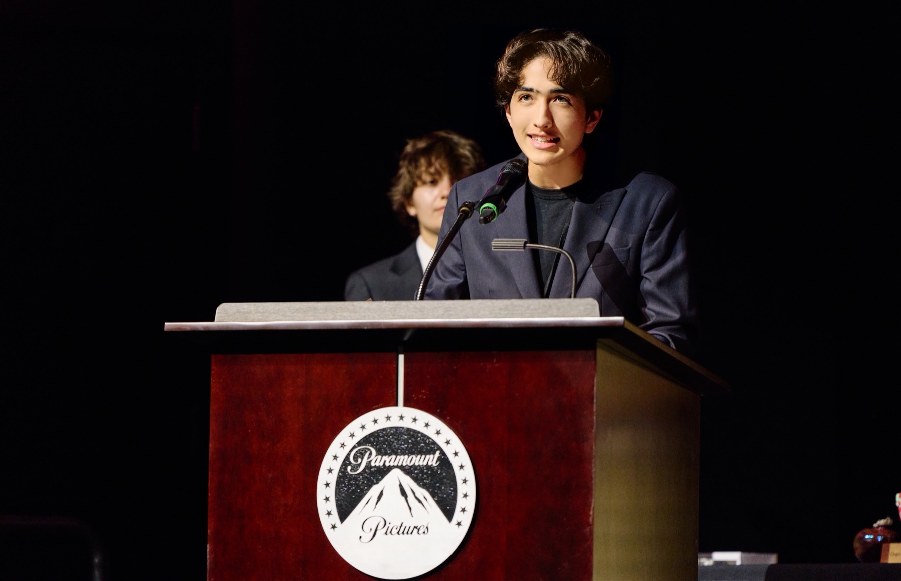 Hudson Hillin speaking at a podium bearing the Paramount Pictures logo